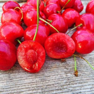 Büttners Rote Knorpelkirsche | Kirschbaum - Kirschen auf einem Tisch sowie die zwei Hälften einer Kirsche