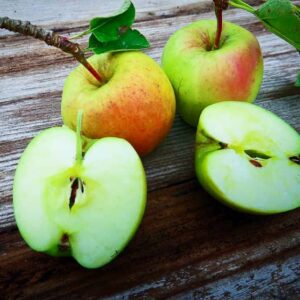 Gelber Ratzeburger Kantapfel kaufen | Apfelbaum - zwei Äpfel und 2 Apfelhälften auf dem Tisch