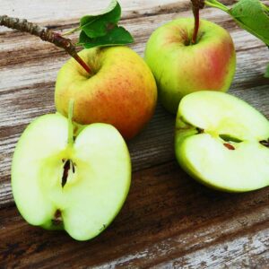Gelber Ratzeburger Kantapfel | Apfelbaum - zwei Äpfel und 2 Apfelhälften auf dem Tisch